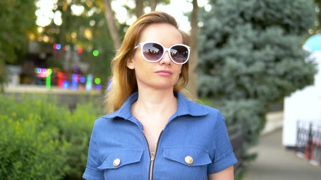 Portrait. fashionable lifestyle. to close. young blond woman with long hair in sunglasses walks in the park, stylish casual outfit