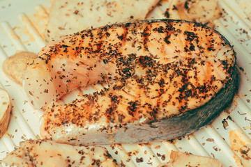 Photo of salmon. Fresh red fish rich color. Mushrooms and chicken fillet on the grill. in spices, dried basil, salt, pepper. Salmon inon the electric grill basil marinade. Recipe. 