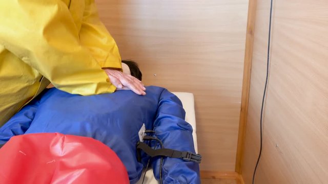 Lifeguard in yellow raincoat learns to do compression heart massage on the mannequin, hands closeup. Refresher courses for rescuers.