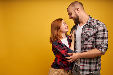 Internal love. Profile side view photo of handsome boyfriend girlfriend ready for kiss hugs touching looking into eyes dressed in checkered shirt isolated on yellow background