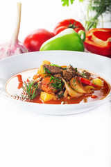 Hot beef hungarian  goulash soup with paprika, beef, potatoes, carrots, onion, pepper and herbs. Ingredients for dish.  White background. High key.