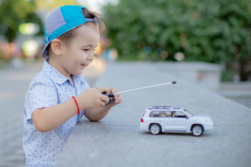 a boy playing with a car remote.a small child playing in the Park with a toy car white controls it remotely