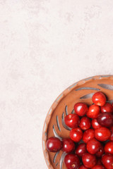 Red sweet cherry in a clay plate on a cream table