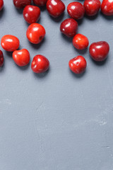 Red sweet cherry scattered on a gray background