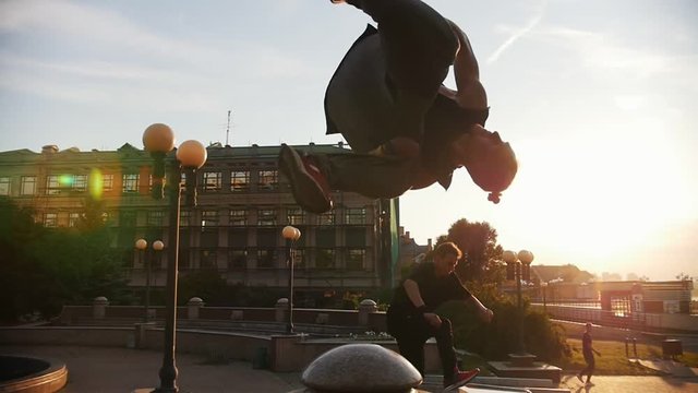 Acrobatic men performing parkour tricks and flips on a background of buildings