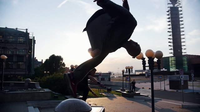 Acrobatic men performing parkour trick - jumping off the border