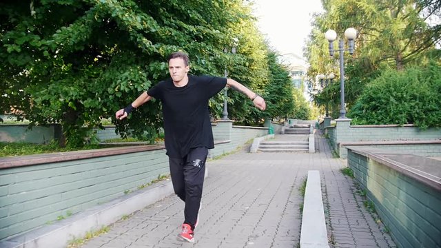 Acrobatic man running in the park and performing a flip in the park