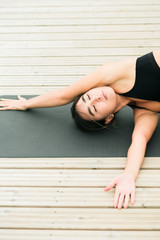 Young Pretty asian girl doing yoga outdoors on the pier by the lake.