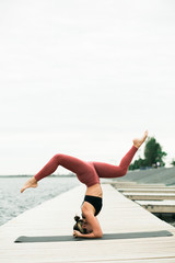 Young Pretty asian girl doing yoga outdoors on the pier by the lake.