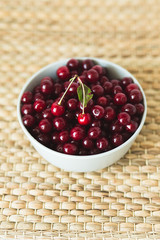 A plate full of fresh cherries on a natural wicker napkin