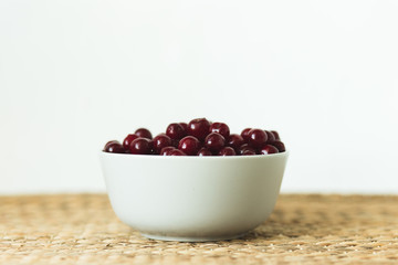 A plate full of fresh cherries on a natural wicker napkin