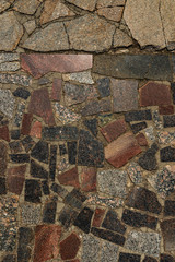 The texture of the sidewalk of chaotic granite stones of different colors with many cracks
