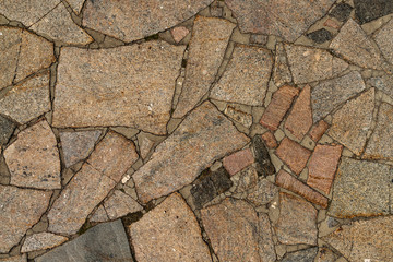 Obraz premium The texture of the sidewalk of chaotic granite stones of different colors with many cracks