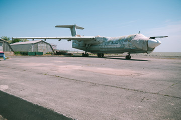 Fototapeta na wymiar abandoned military aircraft on an empty airfield near the hangar against the blue sky. broken plane covered with a cloth on an empty airfield