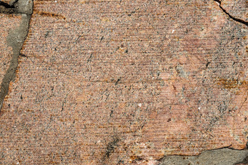 The texture of the sidewalk of chaotic granite stones of different colors with many cracks