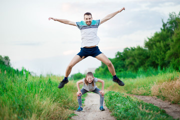 Sport family portrait of handsome father and his cute little daughter play leap frog outdoor at...