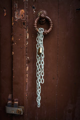 METAL CHAIN AND PADLOCKING IN OLD WOODEN DOOR