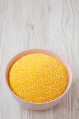Organic Masarepa corn meal in a pink bowl over white wooden background, low angle view. Copy space.