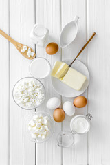 Dairy products from farm with milk, eggs, cottage, butter, yougurt on white wooden background top view