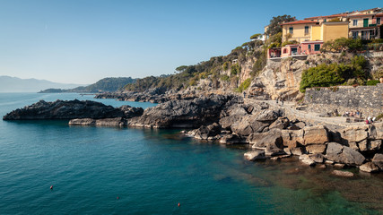 Fototapeta premium Tellaro, La Spezia, Italy. Typical Ligurian maritime glimpse: houses leaning against each other with the typical colors of Liguria above the cliff. Turquoise blue sea