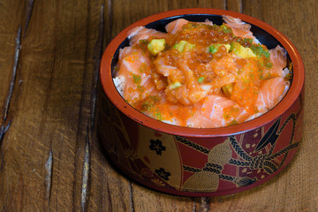 salmon beat with caviar and avocado on a bed of steamed rice served in a large decorated bowl