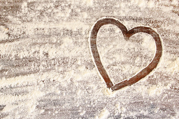 Obraz na płótnie Canvas Ein Herz aus Mehl auf einem Holzbrett
