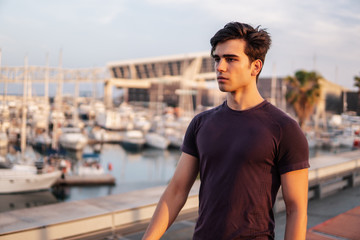 Fototapeta premium Young athletic man running at park with skyscrapers on background. Urban run