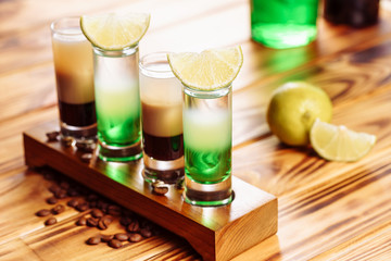 High Glasses with Cocktail B55 Green Mexican Set. Layer Beverage with Brown and White Liquor on Wooden Board and Bar Table for Alcoholic Party. Decorated Ice Cubes, Coffee Bean and Sliced Lime