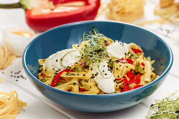 Egg Pasta Tagliatelle Cream Cheese Dish Closeup View. Homemade Spaghetti in Bowl on White Table. Tasty Meal with Microgreen Sprouts, Red Paprika and Mozzarella Ingredients for Recipe. Cooked Rigatoni