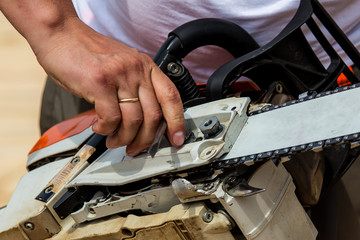 Professional technician working by repair service.Repairing chainsaw in repair shop.