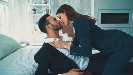 The business man and woman in suits laying on the bed and kissing