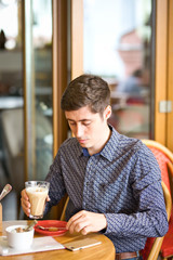 man sitting in cafe and drinking coffee, large latte in man's hands