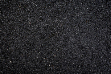 Close-up of wet, black asphalt, viewed from above. High resolution dark full frame textured background.