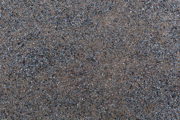High resolution full frame textured background of wet sandy ground with gravel, viewed from above.