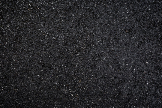 Close-up of wet, black asphalt, viewed from above. High resolution dark full frame textured background.