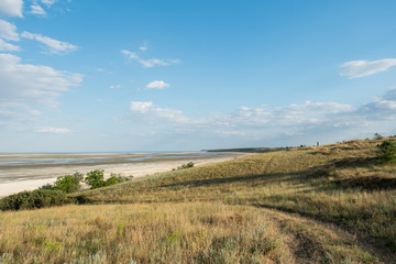 Fototapeta na wymiar Lagoon estuary Molochnyi liman landscape grass path road clouds blue sky