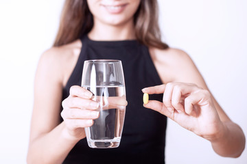 young woman taking medicine pill with water