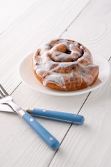 Large gourmet frosted cinnamon roll on white farmhouse table