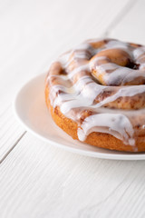 Large gourmet frosted cinnamon roll on white farmhouse table