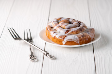 Large gourmet frosted cinnamon roll on white farmhouse table