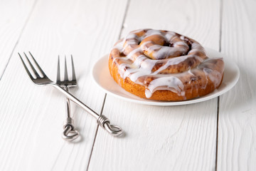Large gourmet frosted cinnamon roll on white farmhouse table