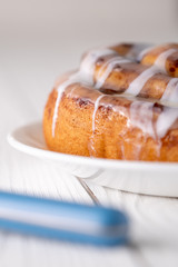 Large gourmet frosted cinnamon roll on white farmhouse table