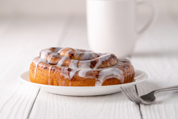 Large gourmet frosted cinnamon roll on white farmhouse table