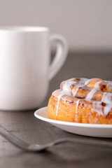 Large gourmet frosted cinnamon roll on brown distressed table.