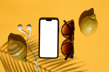 Summertime blank smartphone composition with fresh lemons and sunglasses