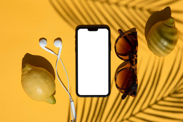 Summertime blank smartphone composition with fresh lemons and sunglasses