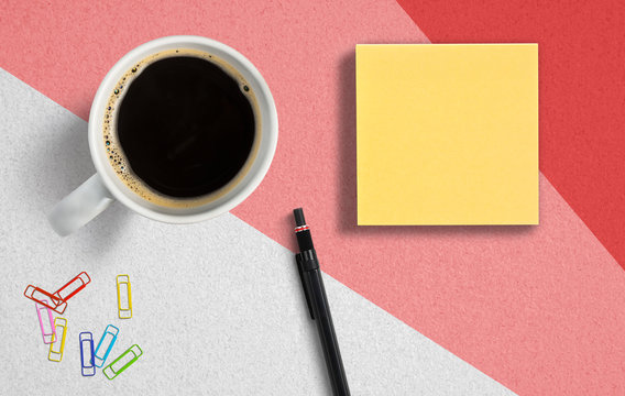 coffee cup with sticky notes, pen and paper clips on paper background