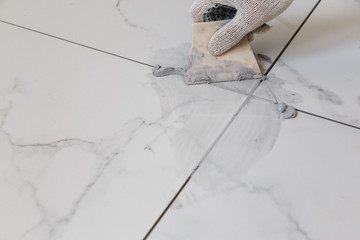 Grouting tiles seams with a rubber trowel