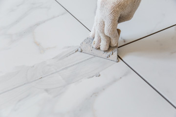 Grouting tiles seams with a rubber trowel.