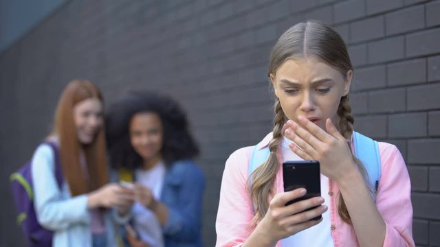 Embarrassed female teenager reading humiliating news in social networks, abuse